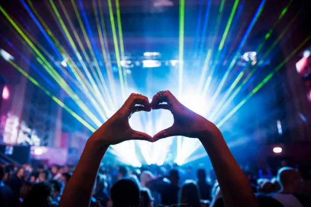 woman making heart shape with hands at music event